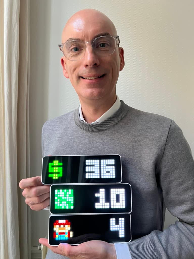Three digital pixel displays showing MRR Calendar metrics while being held